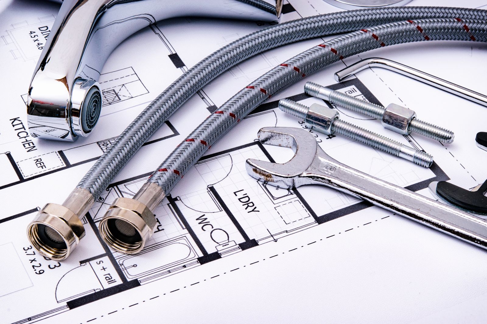 Wrench and pipes laid out on a plumbing sketch